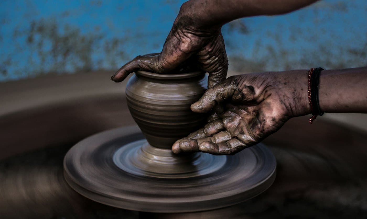 A potter’s hands shaping a clay vessel on a wheel